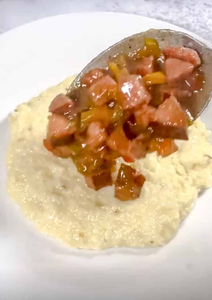scooping andouille sausage gravy over grite