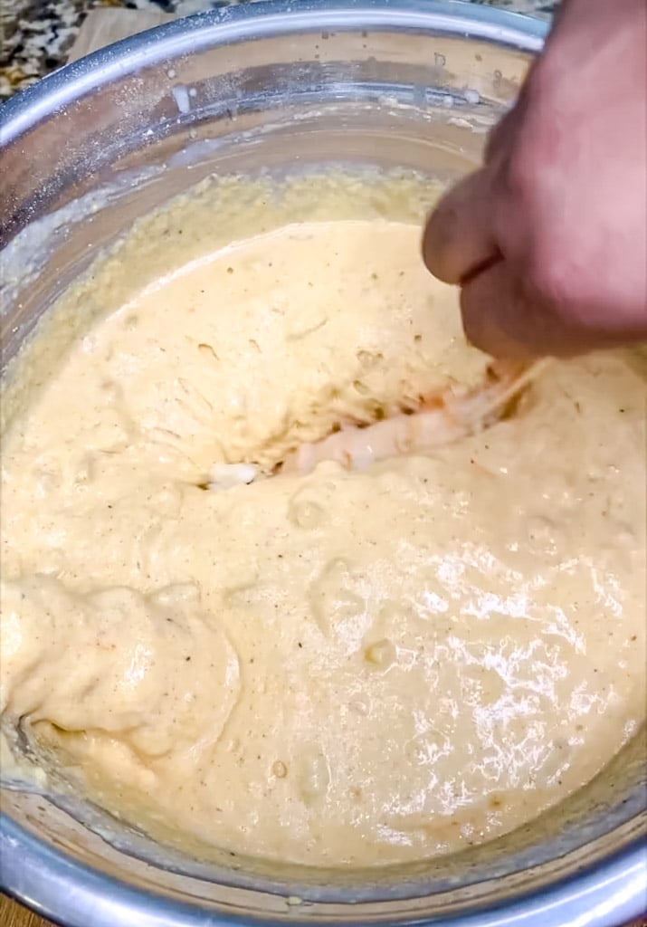 dipping lobster meat into a batter for frying