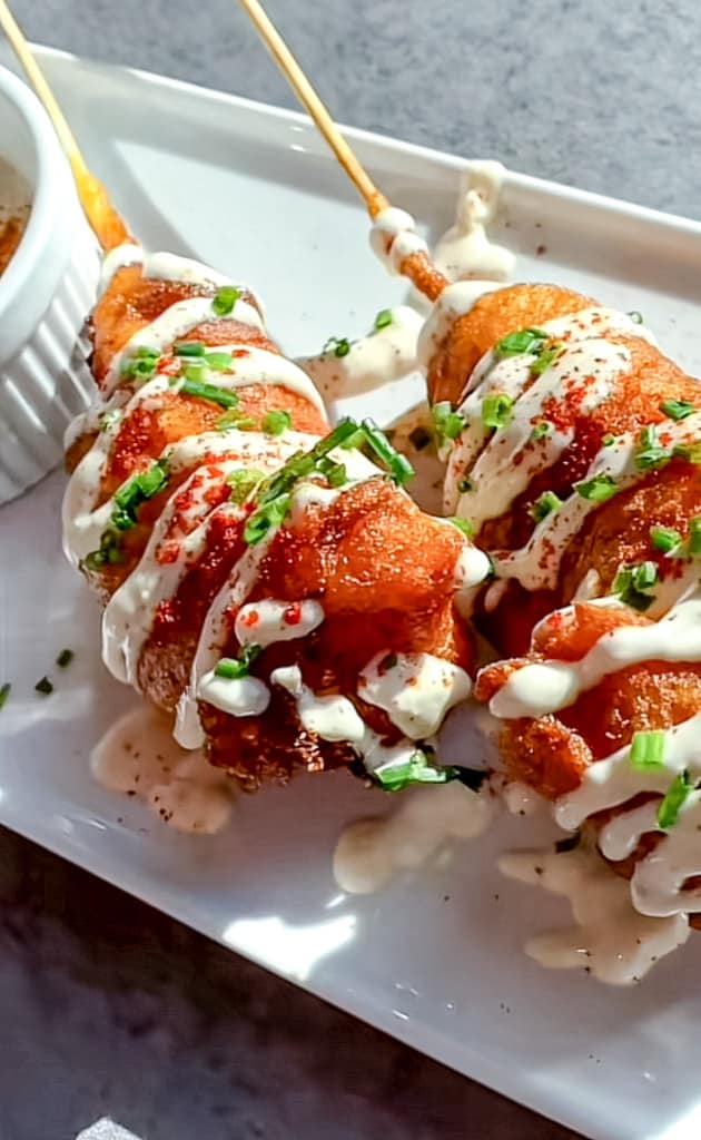 Fried Lobster Tail Corn Dog on a platter with toppings