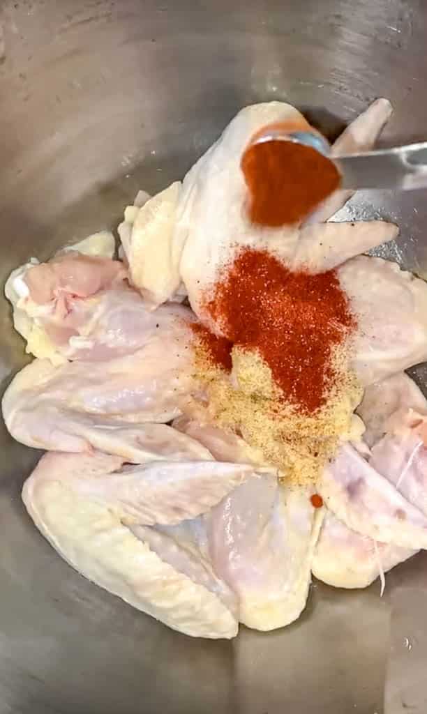 applying seasoning to chicken wings