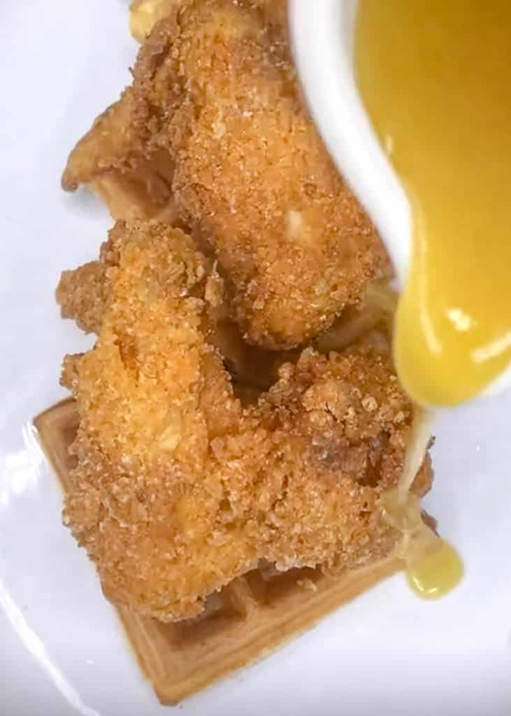 honey butter syrup being poured over breaded chicken wings