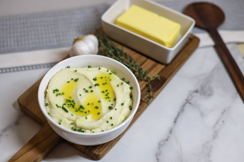 Buttery Mashed Potatoes in a white bowl with chives sprinkled on top