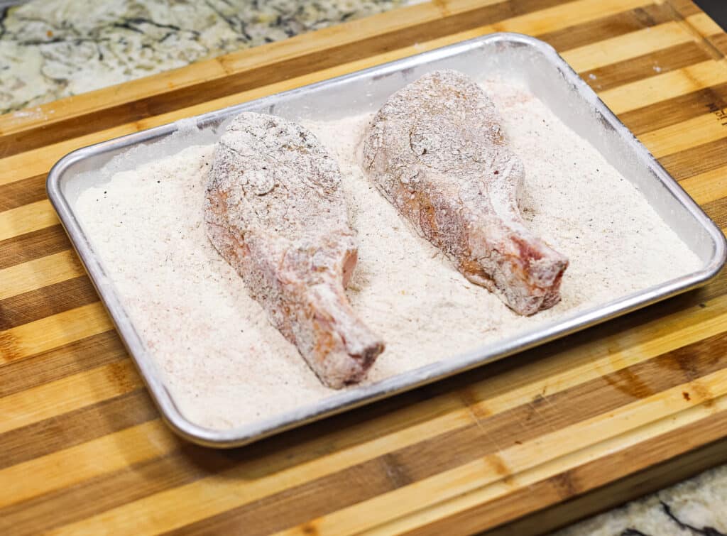 two pork chops on pan coated in flour
