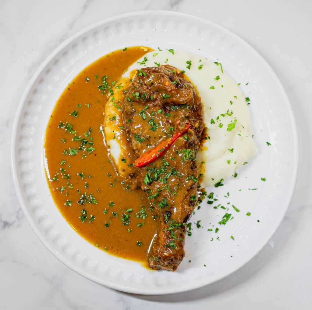 Smothered gravy with mashed potatoes, topped with smothered pork chop on white plate