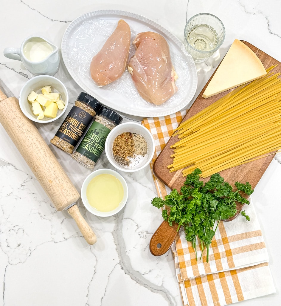 ingredient overhead shot-roller, butter, heavy cream, bayou city seasoning, raw chicken breasts, oil, white wine, parmesan, fettuccine, fresh parsley