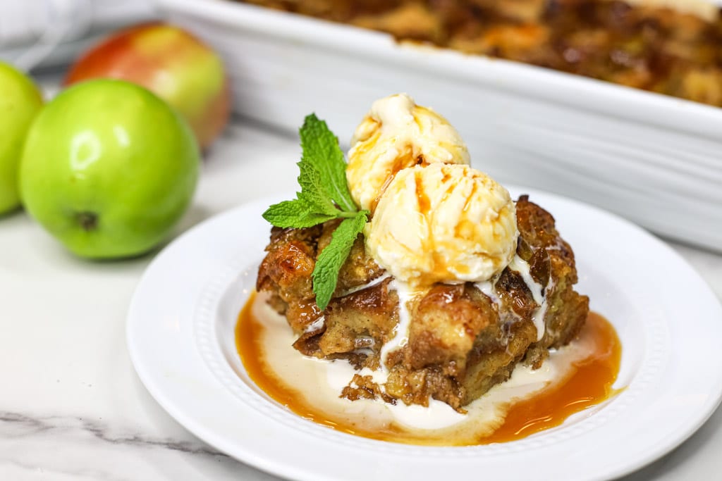 Bread pudding on a white plate with a scoop of ice cream