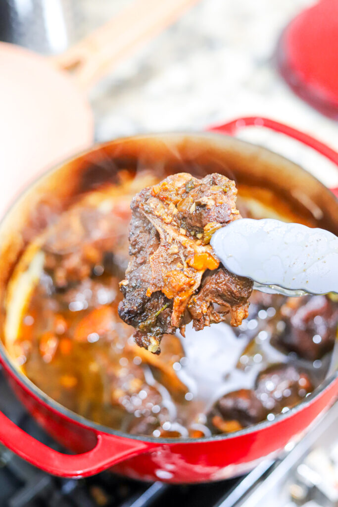 single oxtail being held close to the camera by tongs