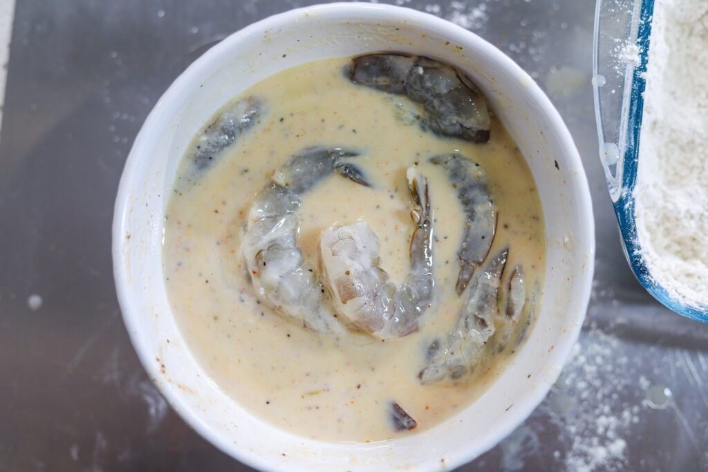 Large shrimp marinating in seasoned buttermilk
