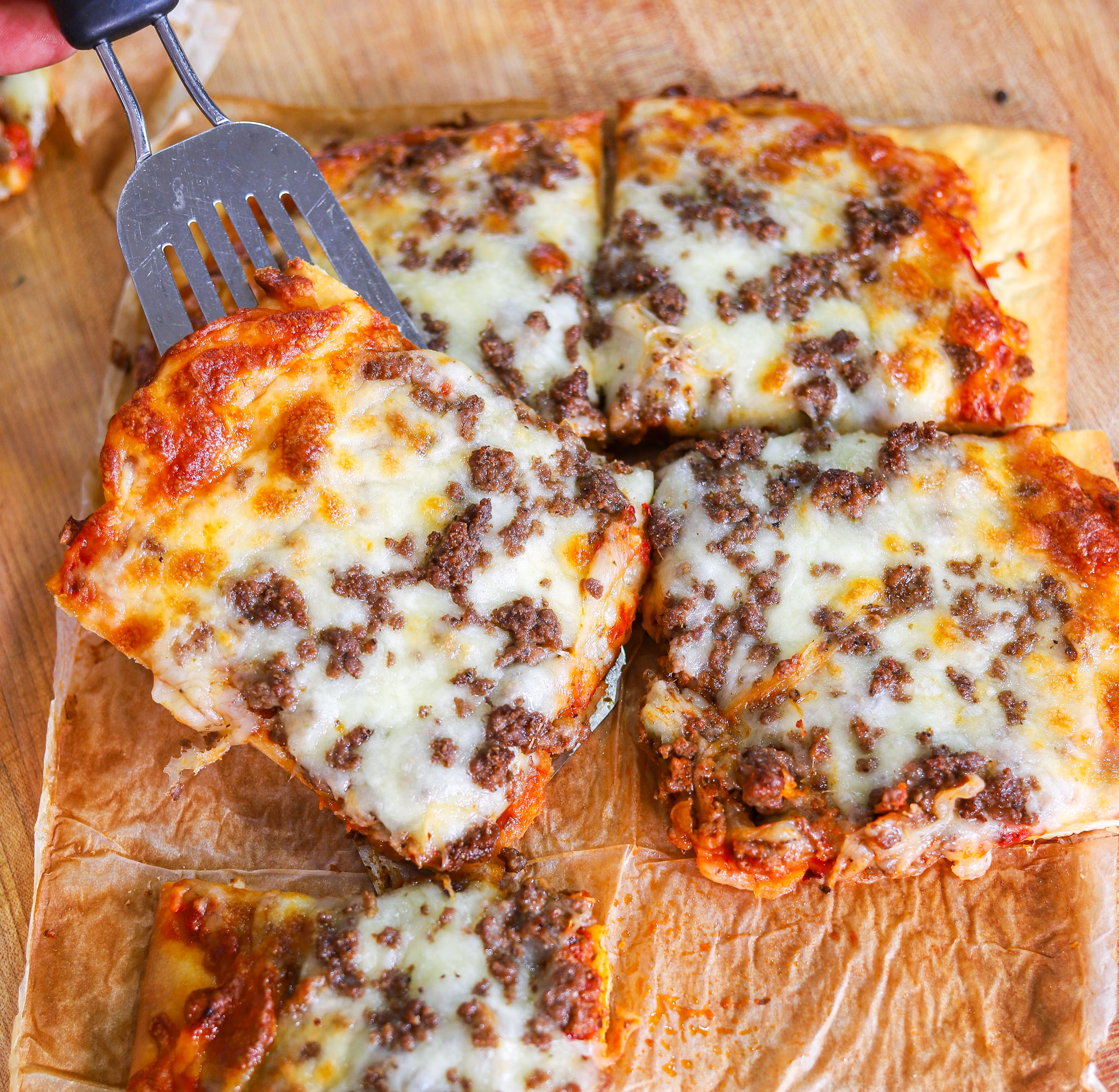 Rectangle school cafeteria pizza slice with seasoned beef, tomato sauce and melted mozzarella