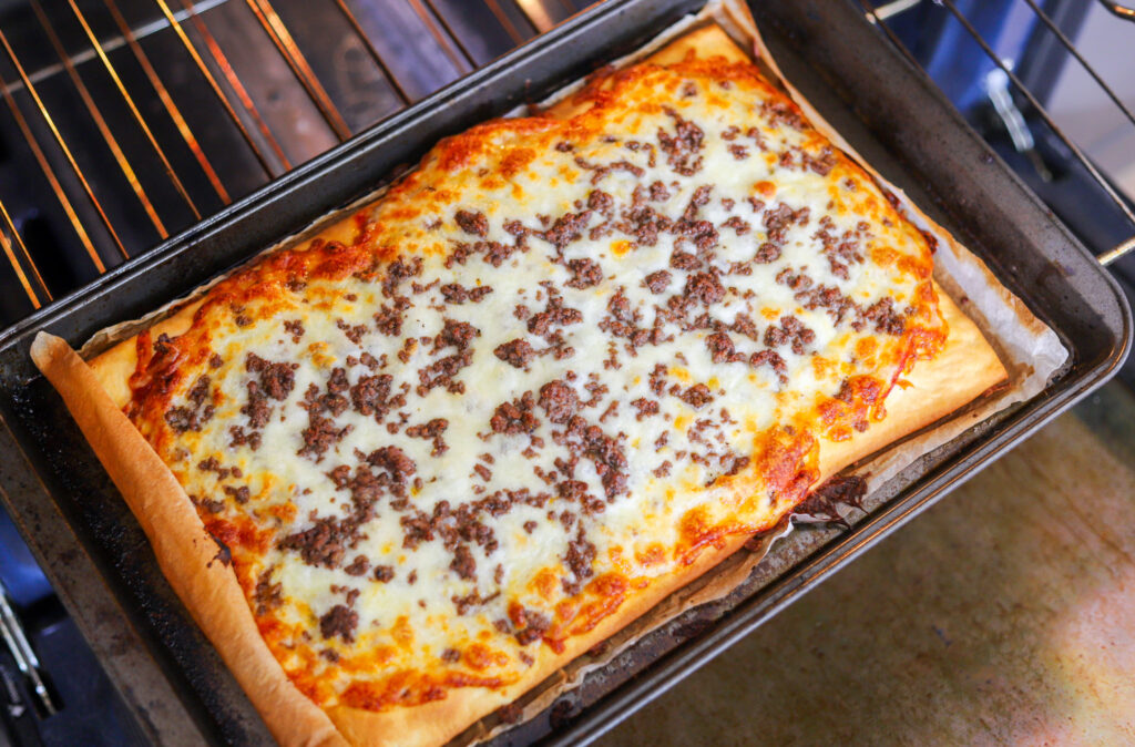 Homemade school lunch pizza baked on a sheet pan with ground beef and cheese