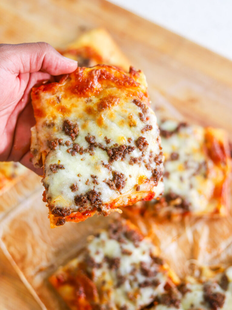 Rectangle school cafeteria pizza slice with seasoned beef, tomato sauce and melted mozzarella