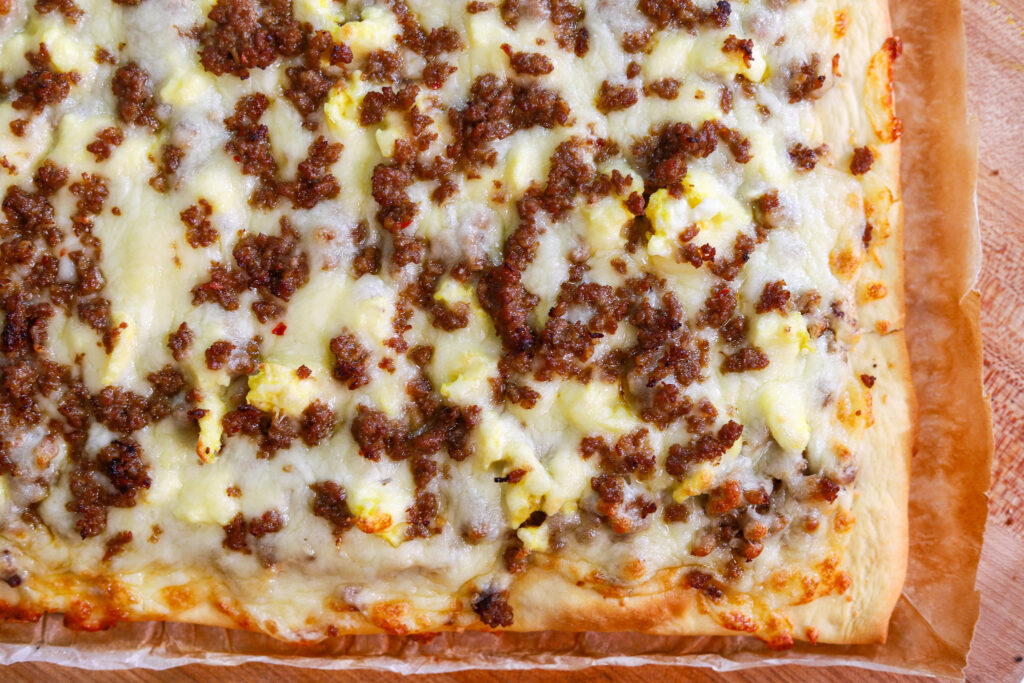 breakfast pizza topped with scrambled eggs and sausage