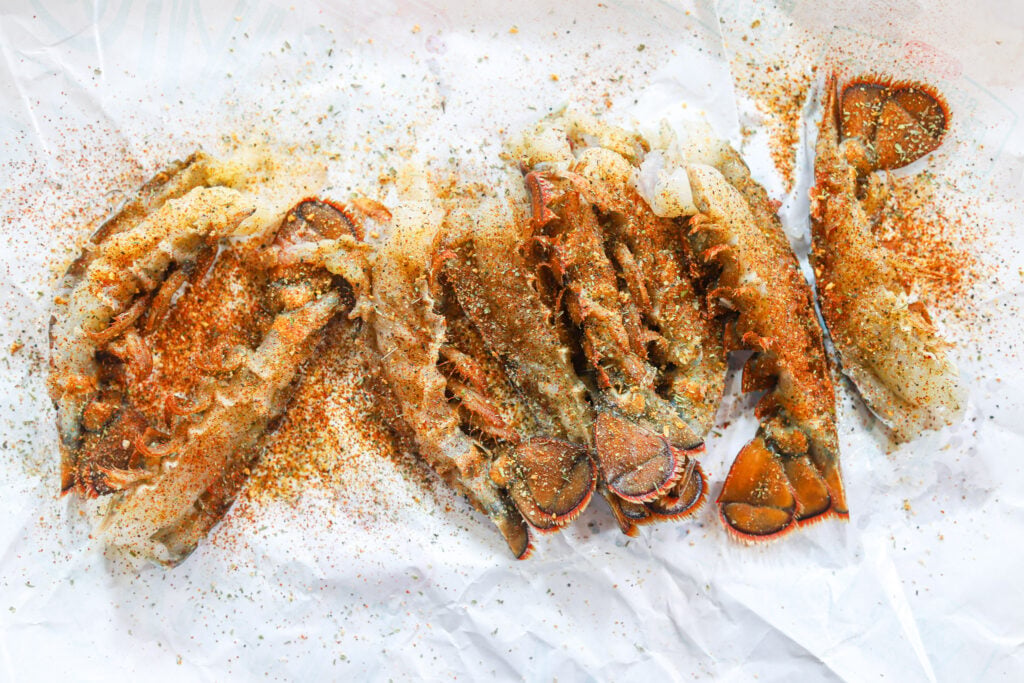 Fresh lobster tails sliced in half lengthwise with the meat exposed and ready for cooking.