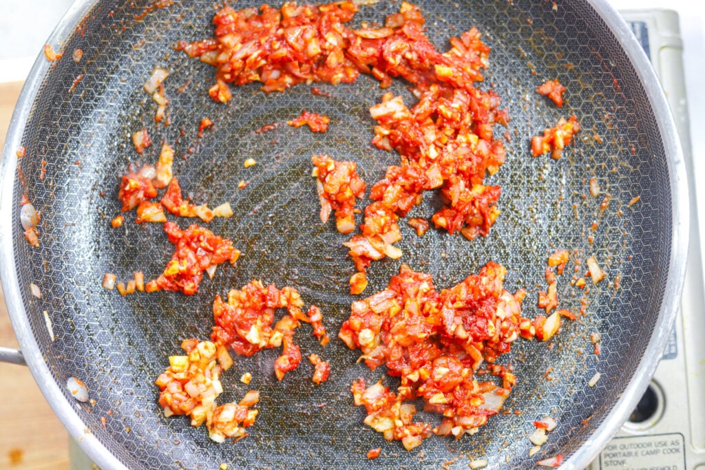 Tomato paste cooking with garlic and shallots to create the base for creamy lobster pasta sauce.