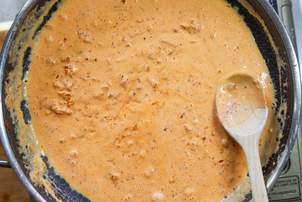 Garlic Parmesan cream sauce with shallots and tomato paste simmering in a skillet